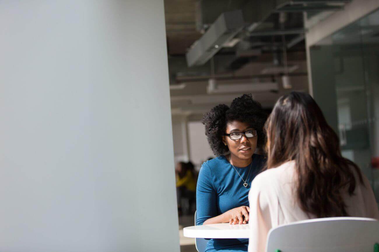 two women talkign to each other at a table