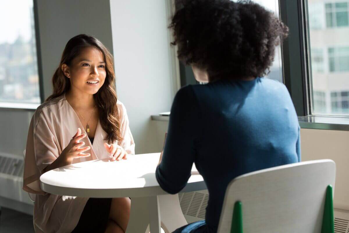 two women talking to each other at a table