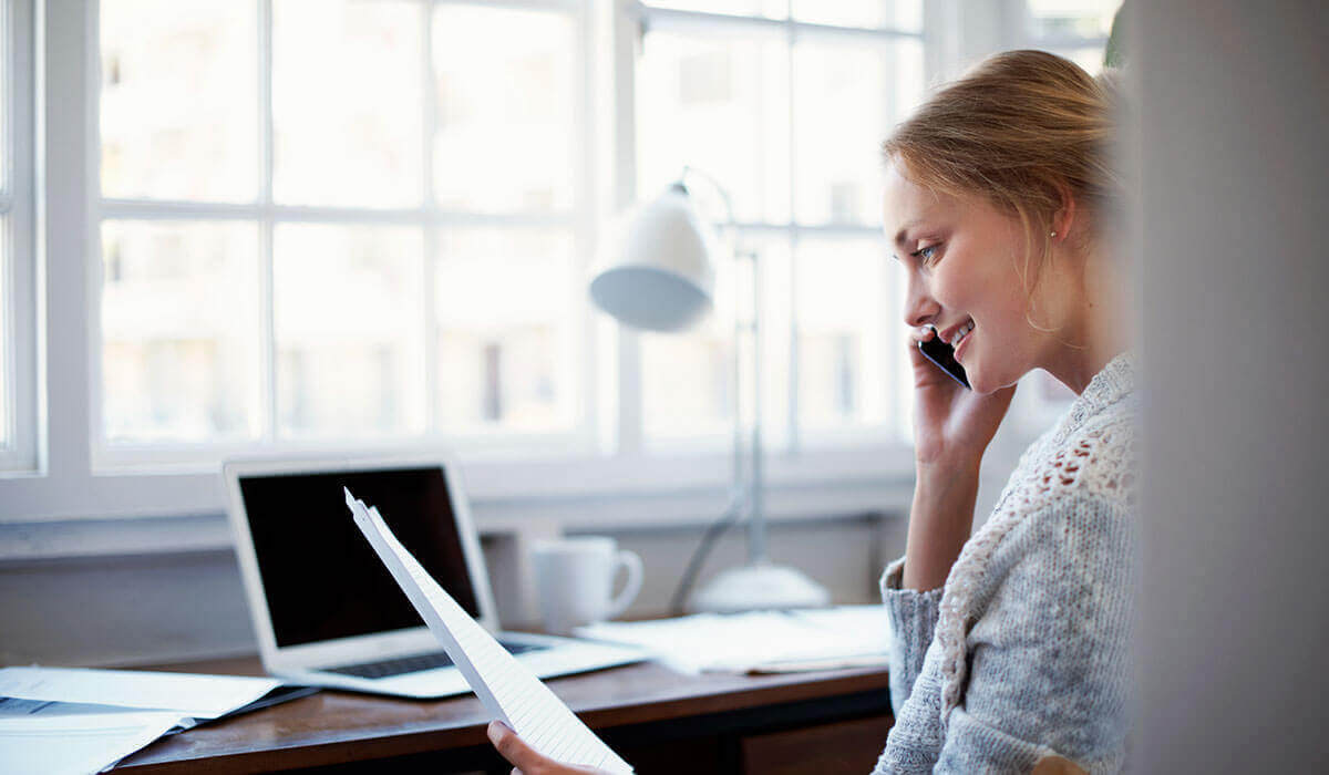 A person holding a smartphone to their ear, appearing engaged in a phone interview, demonstrating remote communication skills and professionalism in the hiring process.