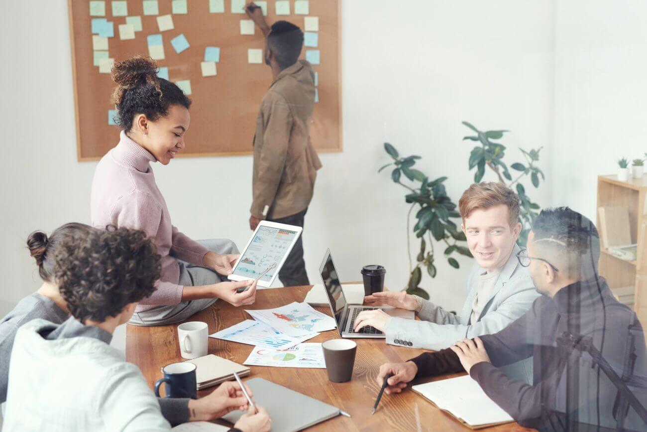empoyees discussing at a table while some presents on cork board