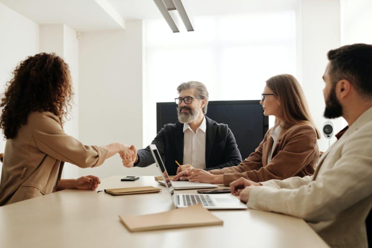 group of four people discussing at a table and shaking hands