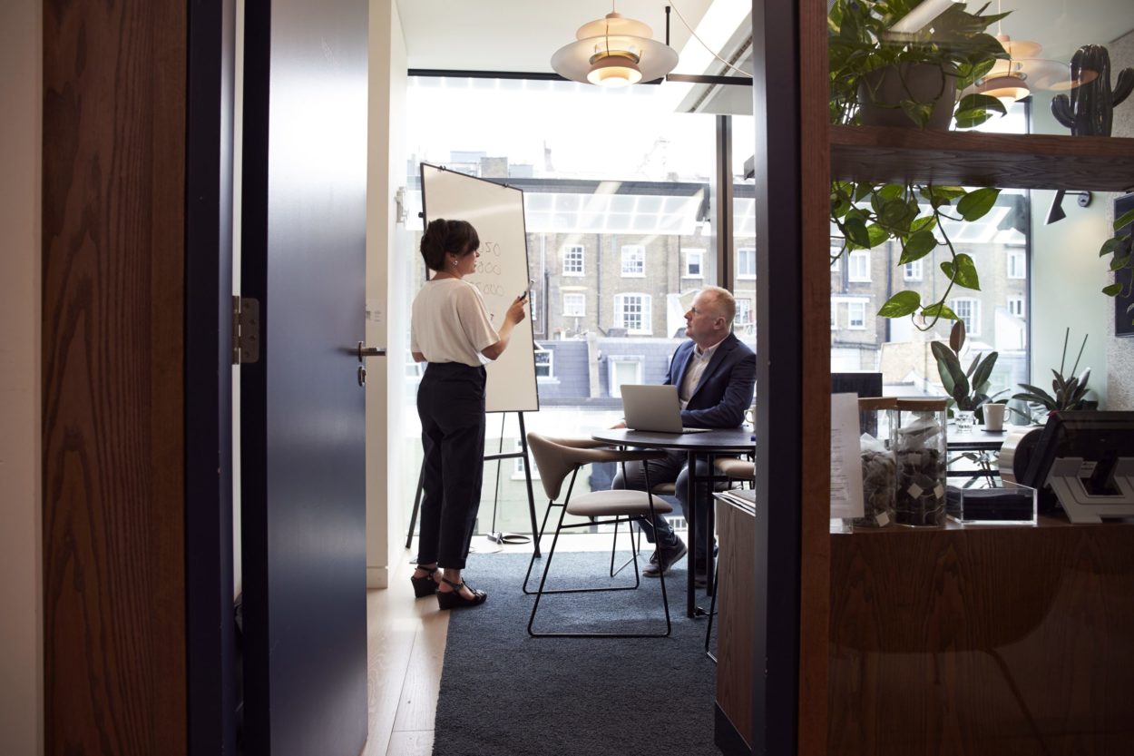 A serene coworking space with minimalist decor, featuring desks, chairs, and potted plants, inviting a calm and focused atmosphere conducive to productivity and creativity.
