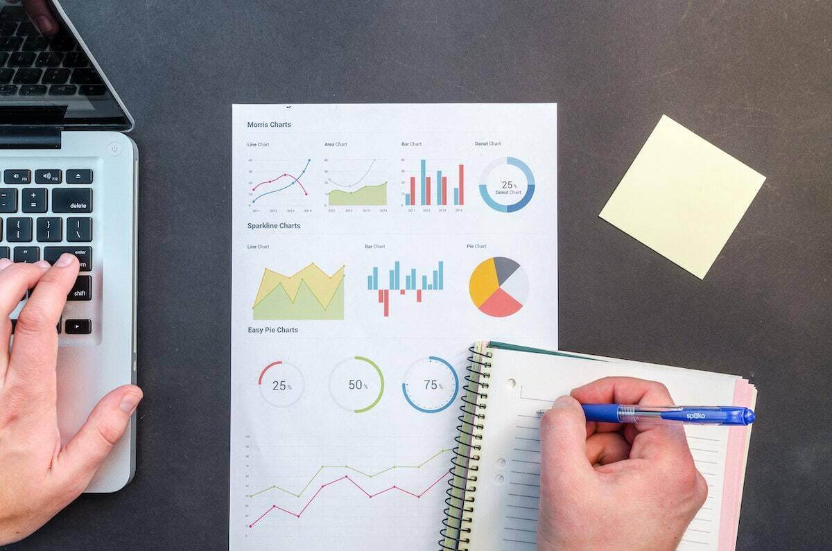 someone at a desk looking at graphs and writing in a notebook
