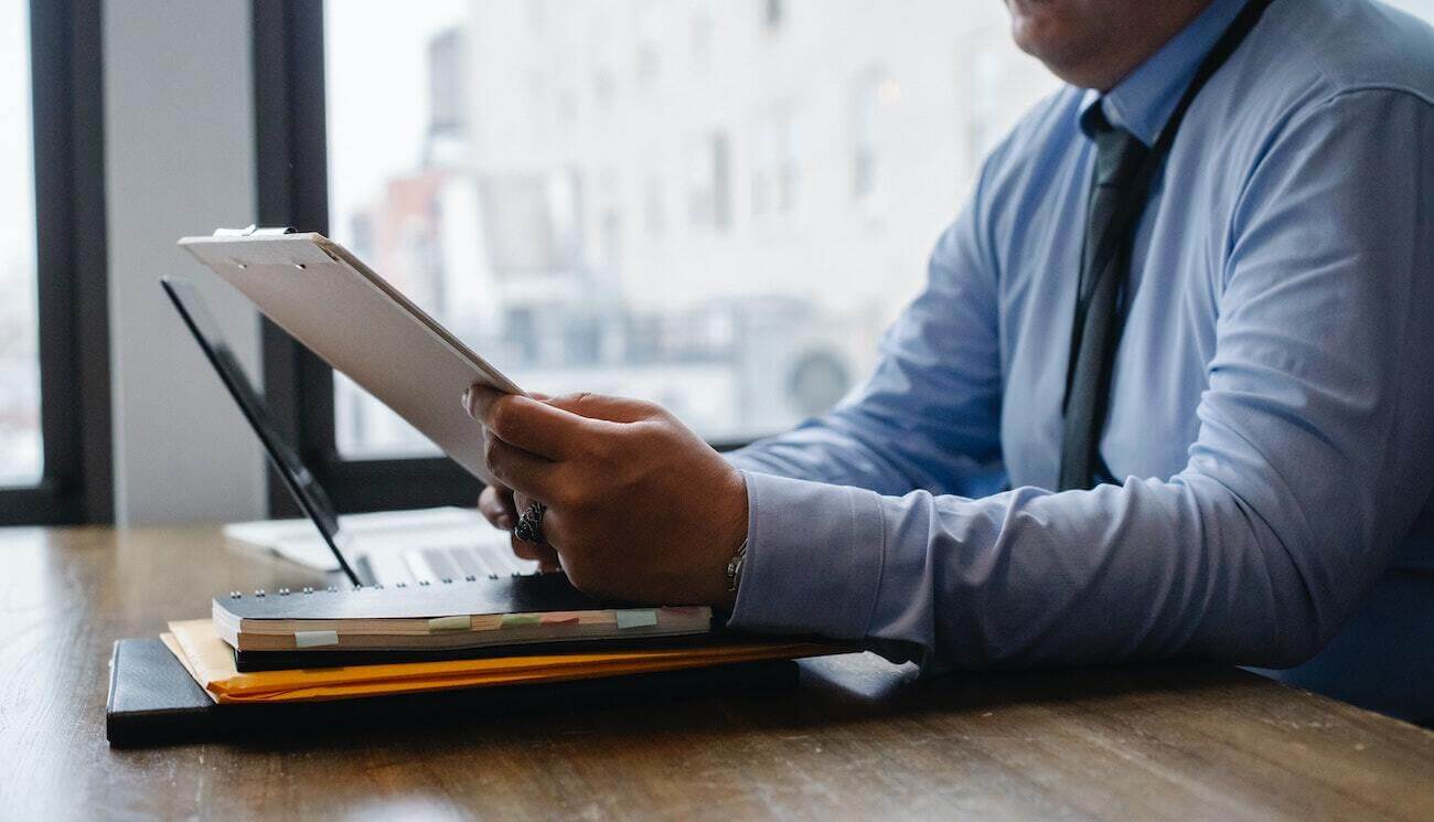 man sitting at a desk looking at a notepad