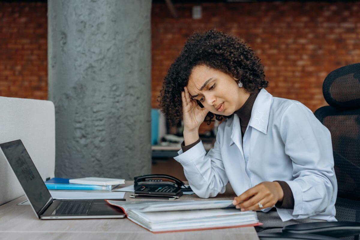 woman at a desk looking stressed at a piece of paper feeling stagnant at her job