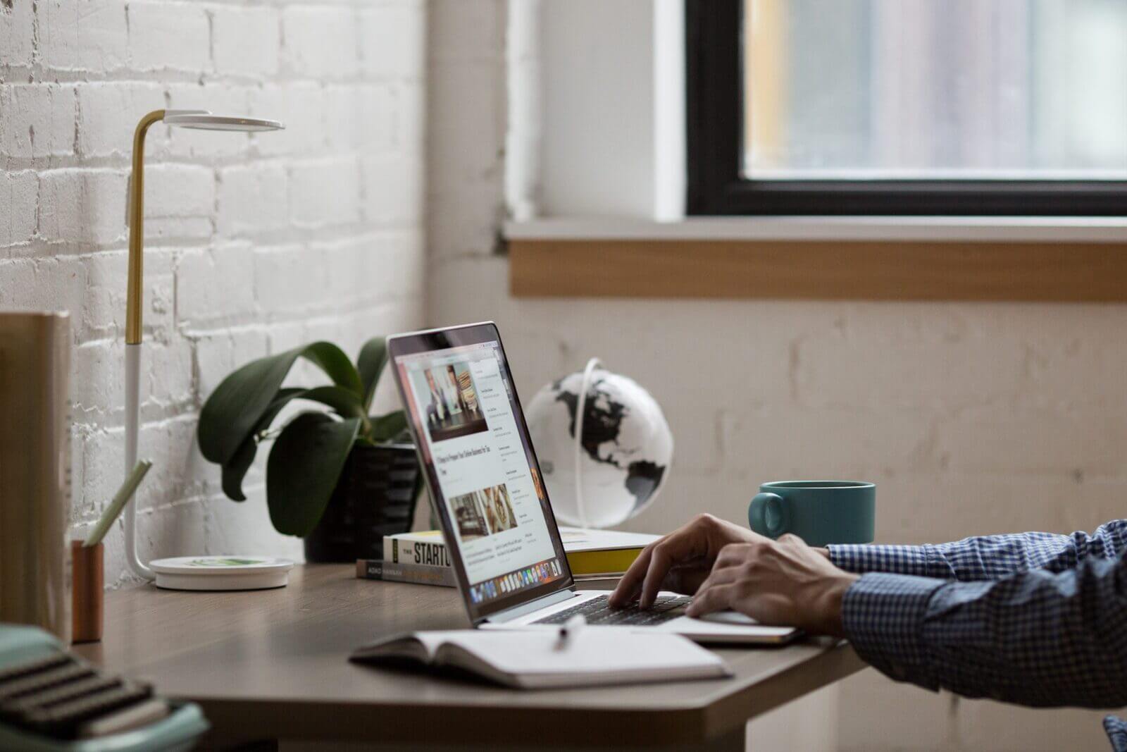 A remote professional typing at a computer in a home office researching hiring trends