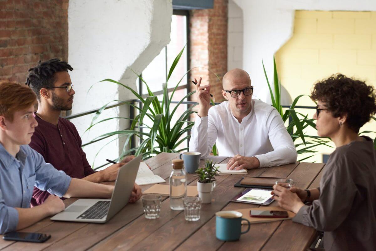 a group of people sitting at a table having a work meeting about preventing a toxic workplace