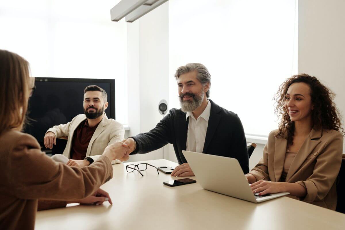 four people at a table where two of them are shaking hands after discussing AI