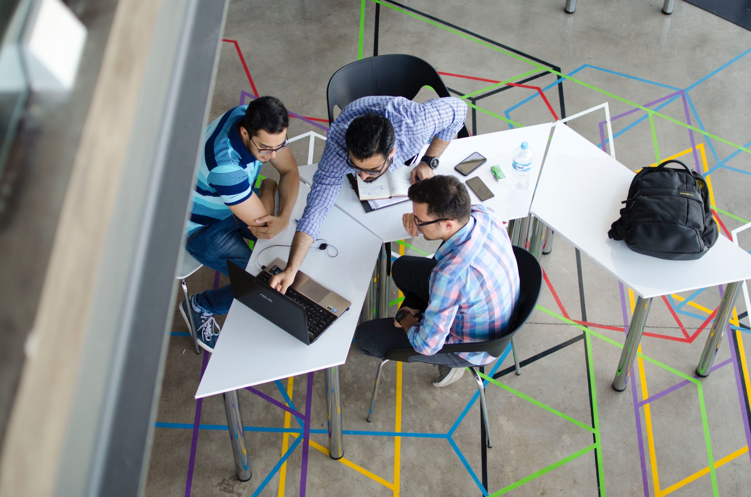 An overhead view of a diverse group of professionals gathered around a table in a bright and modern office space.