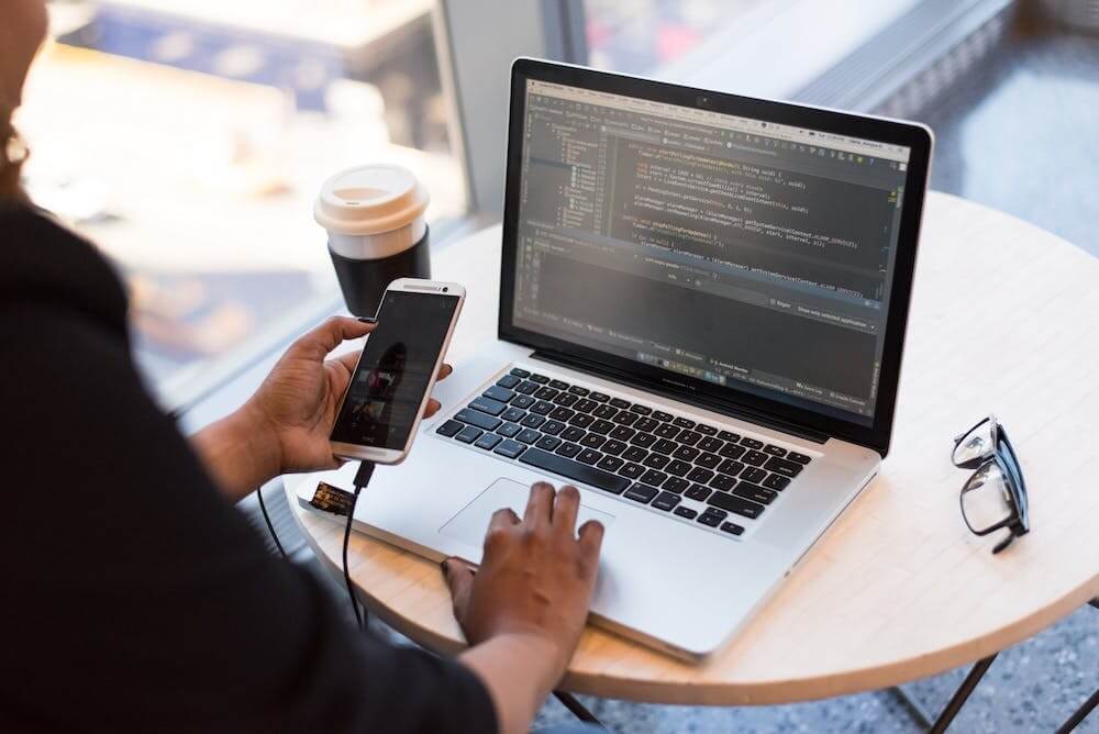 a person on their laptop and phone researching how staffing plays a role in digital transformation