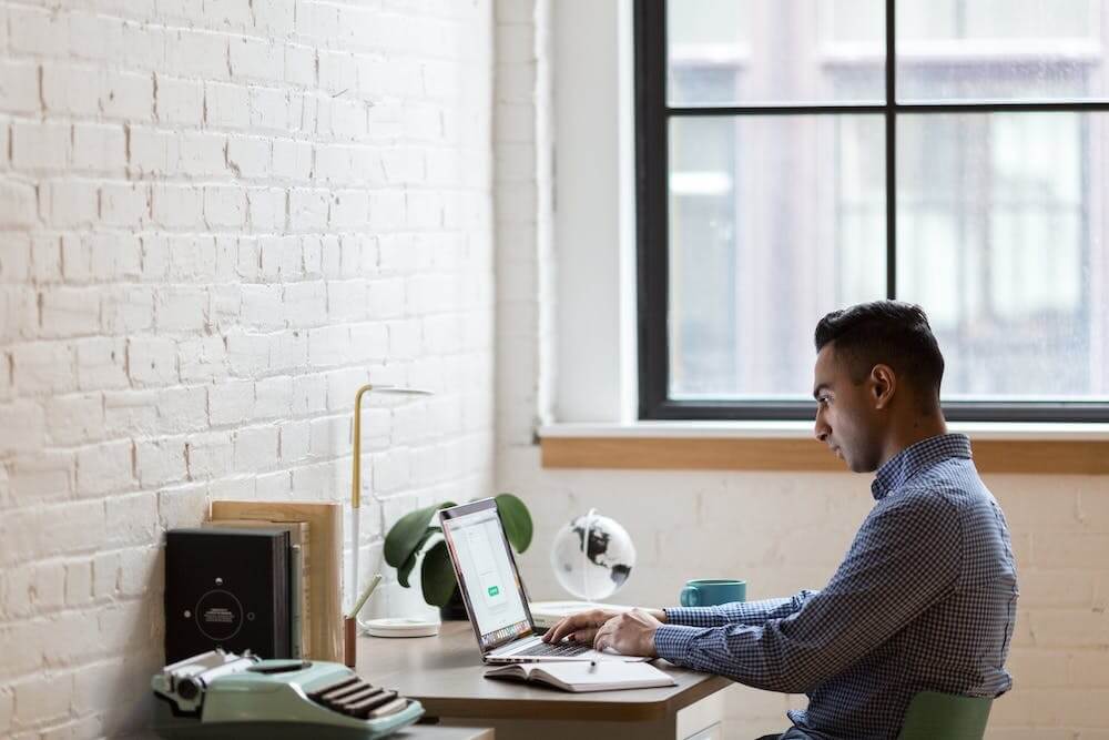 a man sitting at his desk on his computer scheduling his workday to be the most productive