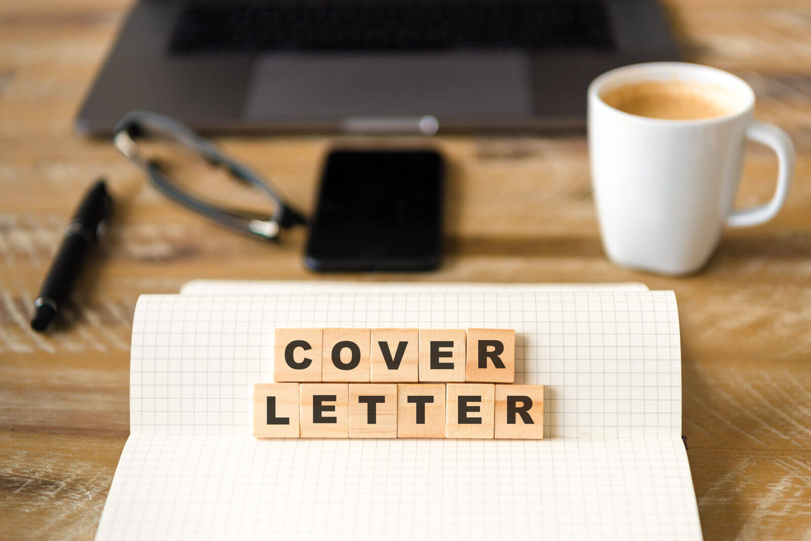 a book with scrabble tiles that spell out cover letter sitting on a desk