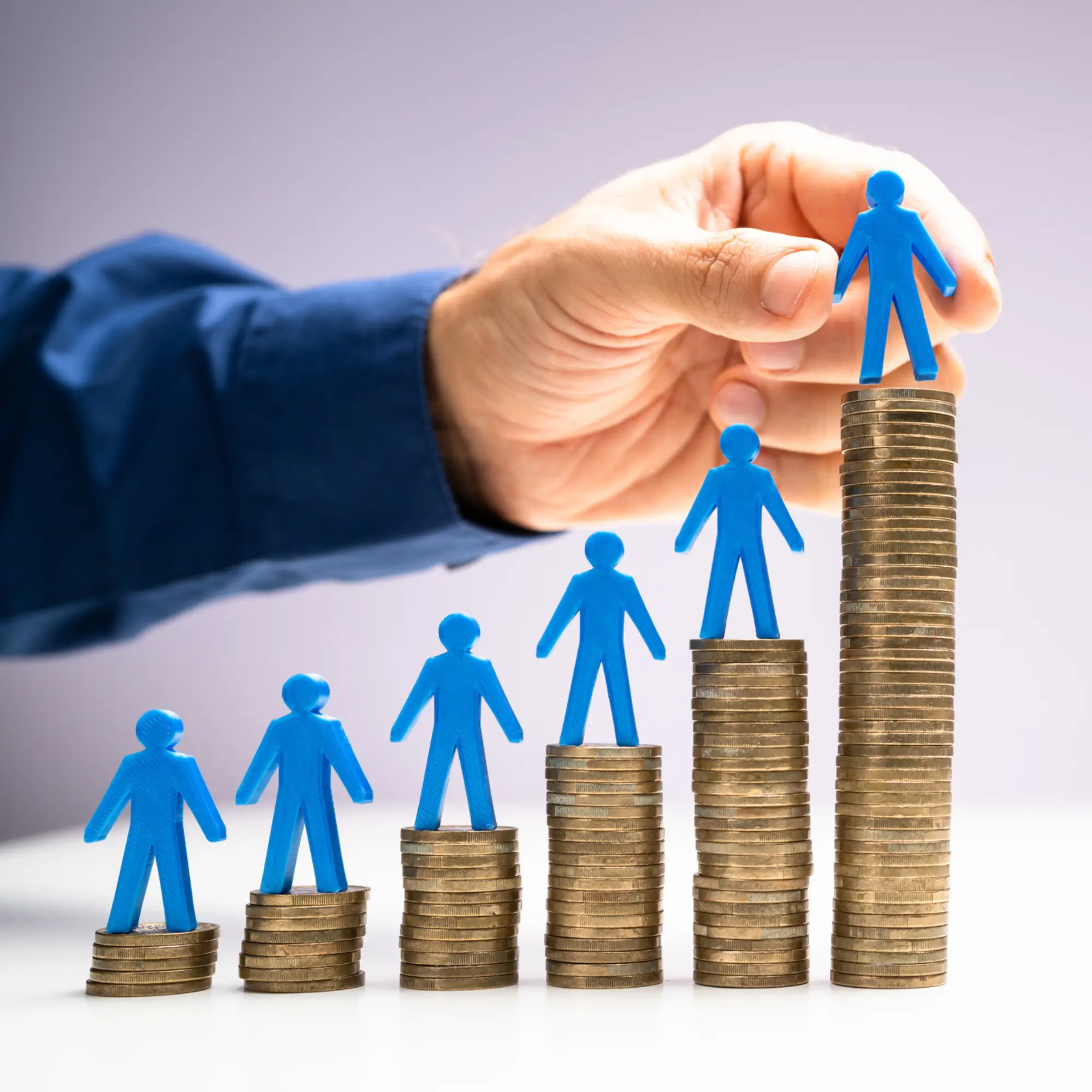 Stacks of coins with man placing people figures on top.