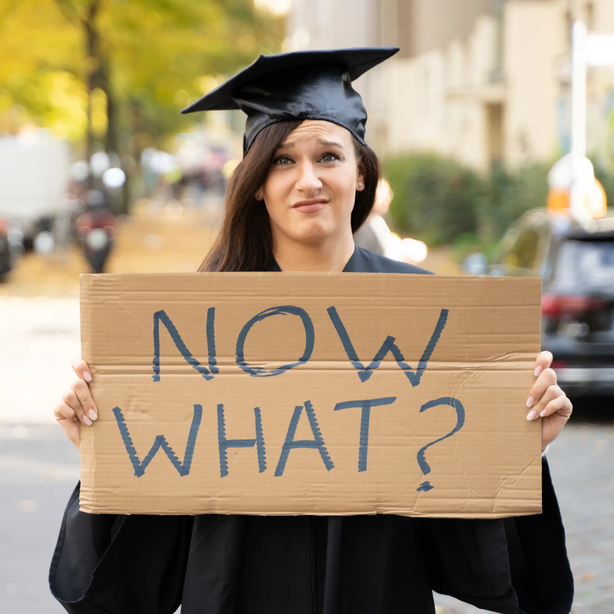 A college graduate holding a sign that says 