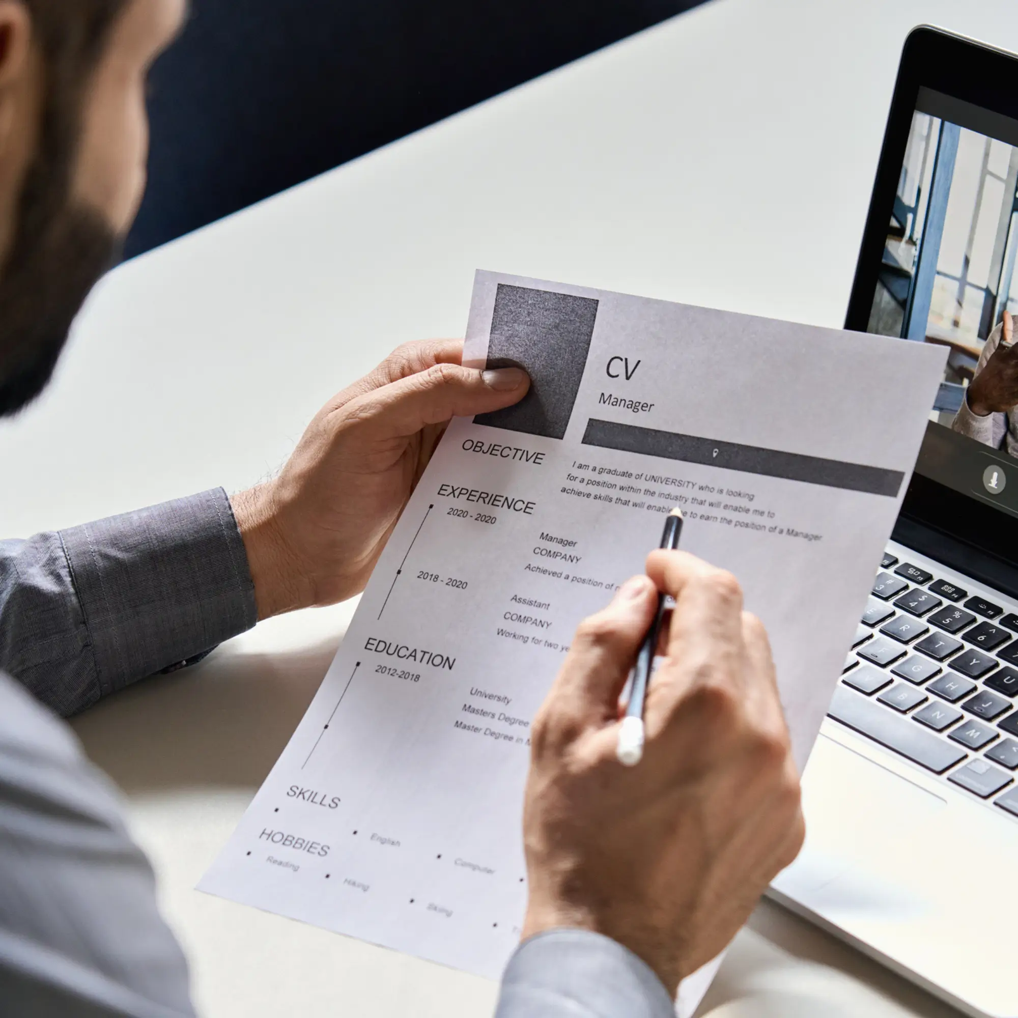 Manager reviewing an IT professional's resume at their desk.